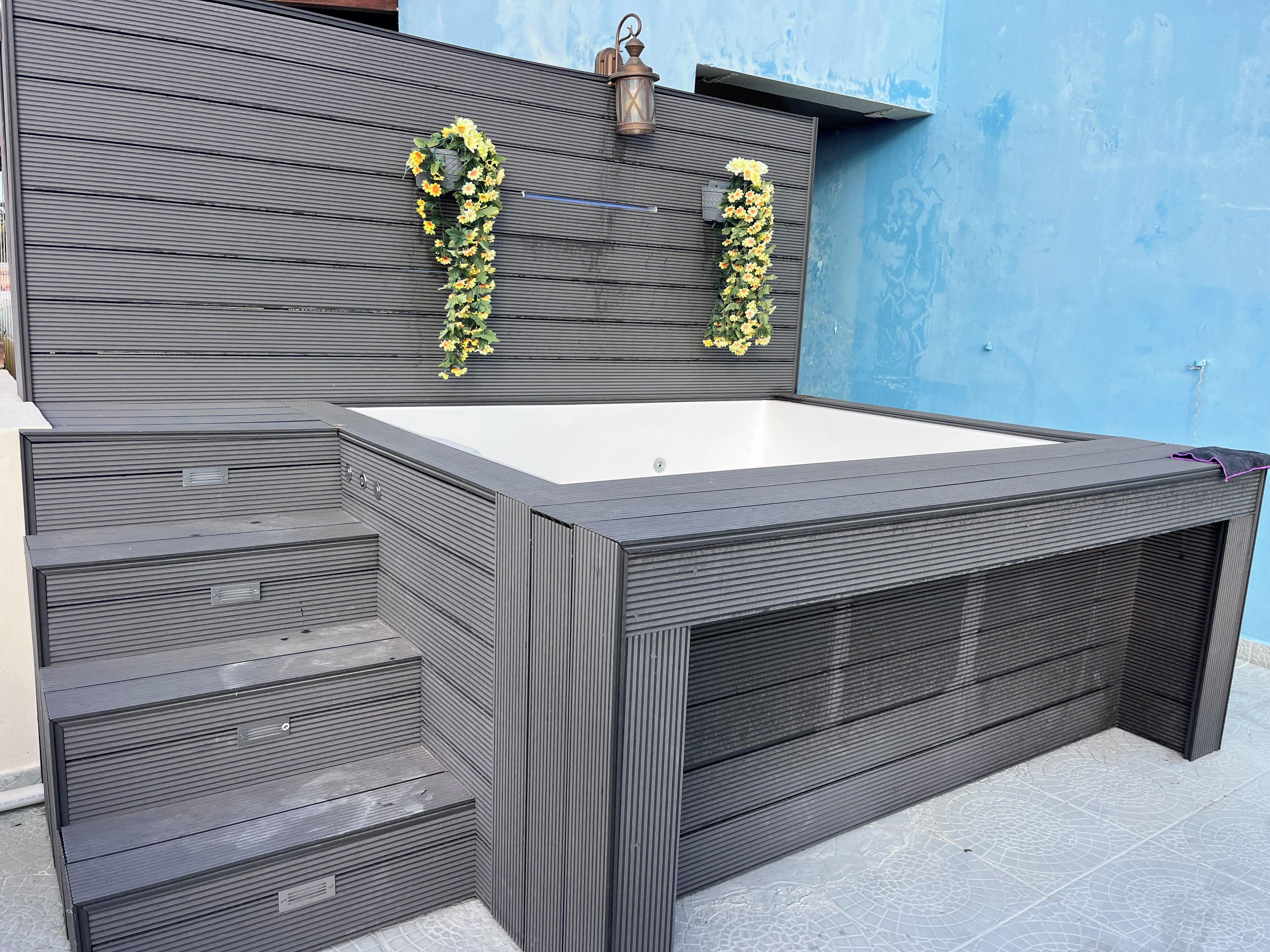 Ein moderner Outdoor-Whirlpool mit rechteckiger Form und integriertem Sitzbereich.