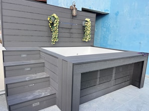Ein moderner Outdoor-Whirlpool mit rechteckiger Form und integriertem Sitzbereich.