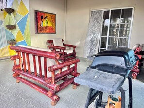 Ein Zimmer mit einer Hängematte, einer Holzbank und einem Grill.