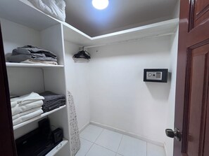 Ein kleines Zimmer mit weiß gefliestem Boden, einer Tür mit runder Klinke und einer an der Wand montierten Sicherheitsvorrichtung.