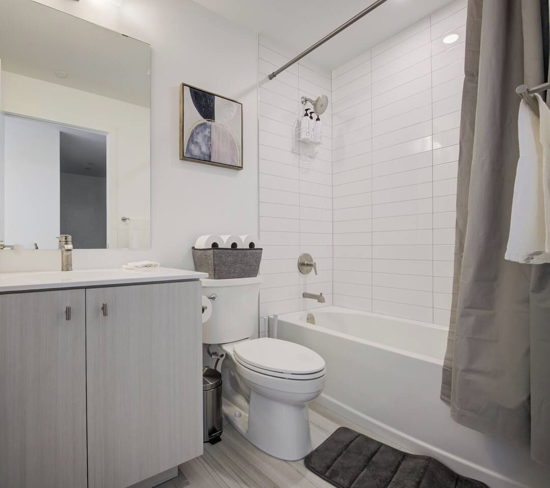 Une salle de bain moderne équipée d’une baignoire, de toilettes et d’un meuble-lavabo.