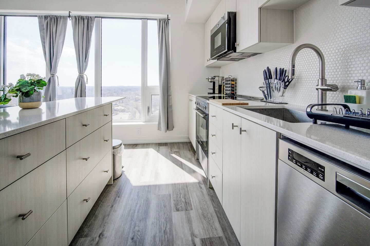 Una cocina moderna con un ventanal grande, electrodomésticos de acero inoxidable y vistas a la ciudad.