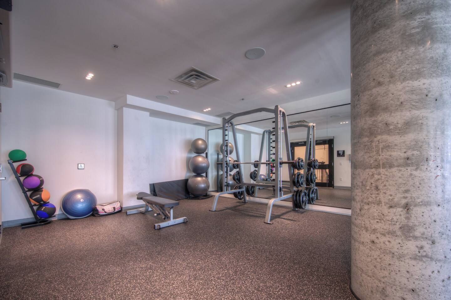A gym with exercise equipment, a bench, and exercise balls.