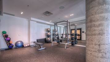 A gym with exercise equipment, a bench, and exercise balls.