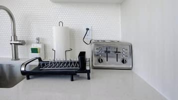 A kitchen with a dishwasher, a sink, and a dish rack.