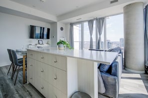 A modern kitchen with a large island, dining area, and a view of the city. - Open concept w/ city views (Kitchener)