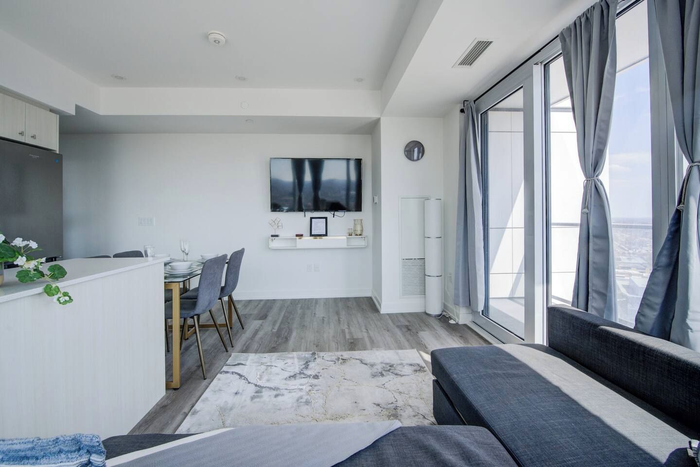 Un espacio de estar moderno con comedor, televisor de pantalla plana y un amplio ventanal con vistas.