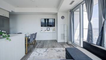 Un espacio de estar moderno con comedor, televisor de pantalla plana y un amplio ventanal con vistas.