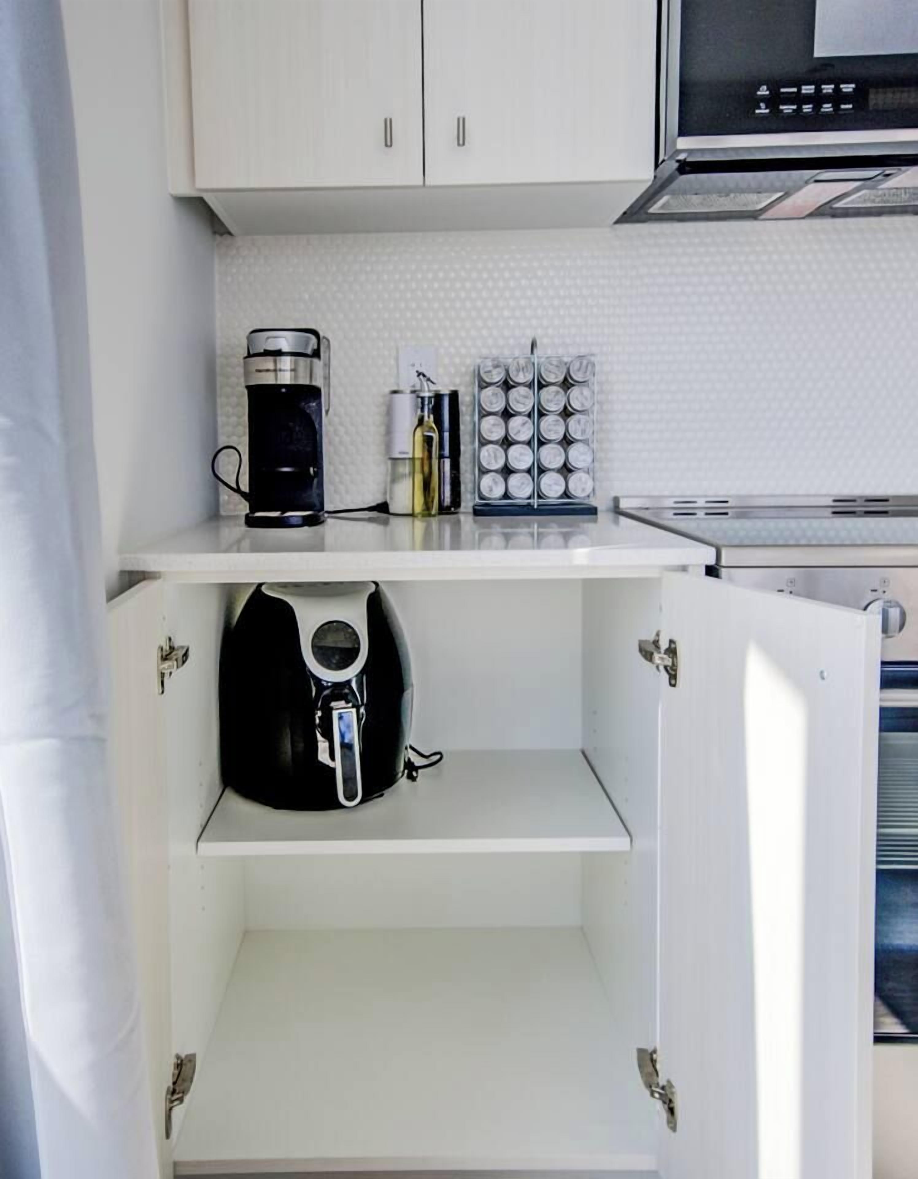 Cozinha compacta com cafeteira, conjunto de recipientes para temperos e micro-ondas.