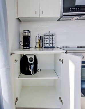 A compact kitchen with a coffee maker, a set of condiment containers, and a microwave. - Open concept w/ city views (Kitchener)
