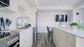 Une cuisine moderne avec des meubles blancs, un four encastré et un coin repas comprenant une table et des chaises.