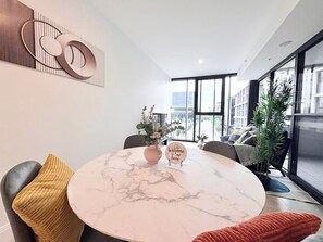 A modern living room with a marble table, a 'Welcome to our home' sign, and a large window offering a city view. - City Center 1BR丨Steps from Lake丨with Parking (Canberra)