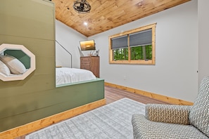 Ein Schlafzimmer mit einem Bett, einem Schminktisch, einem Fenster mit Jalousien, einem Spiegel und einer Deckenleuchte.