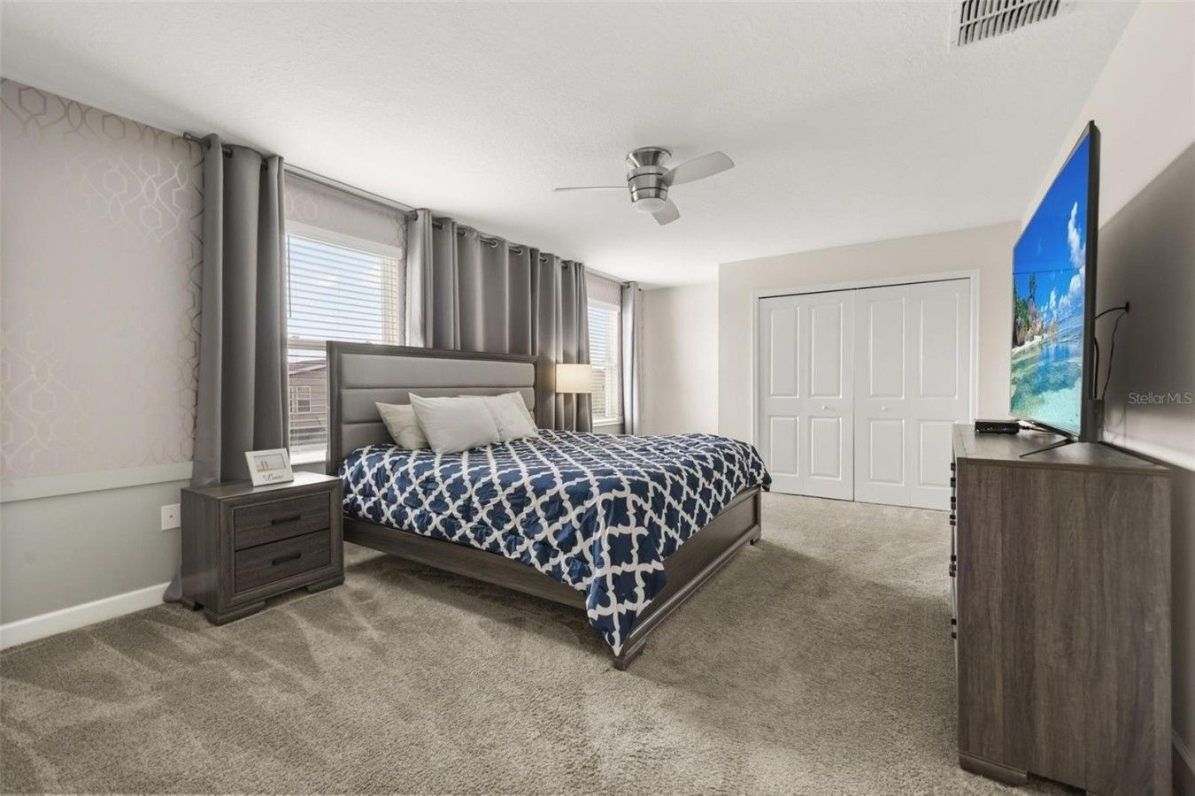 A bedroom with a bed, nightstand, dresser, and a ceiling fan.