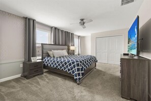 A bedroom with a bed, nightstand, dresser, and a ceiling fan. - Private Pool & Spa | Six-Bedroom ChampionsGate Home (Kissimmee)