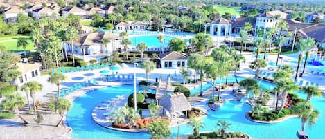 A resort with multiple swimming pools, palm trees, and a golf course in the background.