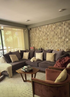 Ein Wohnzimmer mit einer Couch, Sesseln, einem Couchtisch und einem Bücherregal.