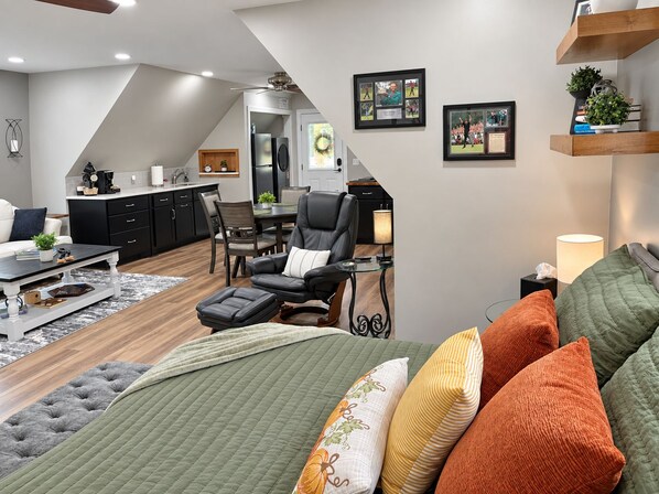 A modern living room with a sofa, a dining area, and a kitchen in the background.
