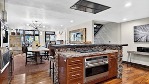 A modern kitchen with a central island, built-in oven, and a dining area with a table and chairs. - Deer Valley Lodge by Avantstay Hot Tub + Cedar Sauna + Elevator + Game Lounge Walk to Main Street (Park City)
