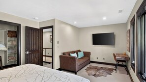 A hotel room with a bed, a brown sofa, a flat-screen TV, a wooden side table, and a rug. - Deer Valley Lodge by Avantstay Hot Tub + Cedar Sauna + Elevator + Game Lounge Walk to Main Street (Park City)
