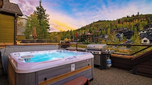A hot tub on a deck with a grill and a barbecue, overlooking a residential area with houses and trees. - Deer Valley Lodge by Avantstay Hot Tub + Cedar Sauna + Elevator + Game Lounge Walk to Main Street (Park City)