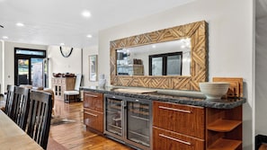 Eine moderne Küche mit Holzschränken, einem eingebauten Kühlschrank und einem großen Spiegel mit geometrischem Rahmen.