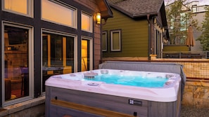 A hot tub in front of a building with large windows and a stone wall. - Deer Valley Lodge by Avantstay Hot Tub + Cedar Sauna + Elevator + Game Lounge Walk to Main Street (Park City)