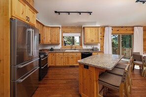 Large kitchen island providing a bar with seating for three and ample counter space for prepping.