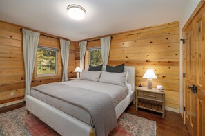 A wooden-paneled bedroom with a bed, nightstands, and a window.