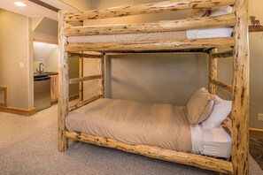 A bunk bed with a wooden frame and beige bedding. - New! Ski-in/Ski-out, Private Hot Tub, BBQ, Lone Peak! (Big Sky)