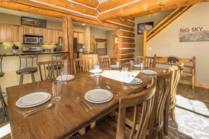 A wooden dining table set for six with plates, cutlery, and glasses. - New! Ski-in/Ski-out, Private Hot Tub, BBQ, Lone Peak! (Big Sky)