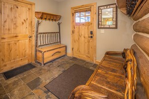 A log cabin interior with a bench, a bench seat, a coat rack, and a door with a window. - New! Ski-in/Ski-out, Private Hot Tub, BBQ, Lone Peak! (Big Sky)