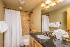 Une salle de bain équipée d’une baignoire, de toilettes, d’un lavabo et d’une douche avec une porte en verre.