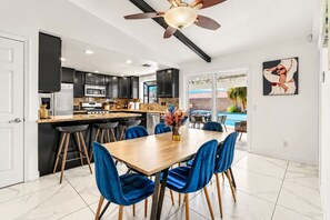 Eine moderne Küche mit dunklen Schränken, einem Holzespeisetisch und blauen Stühlen.
