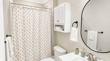 A bathroom with a toilet, sink, mirror, and shower curtain.