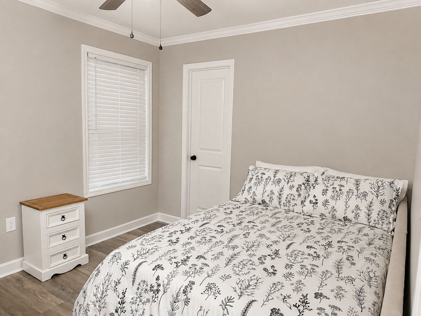 Un dormitorio con cama, cómoda, ventana con persianas y puerta.