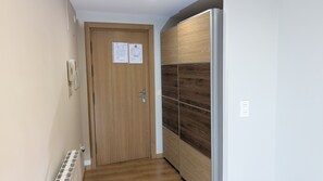 A hallway with a wooden door, a wall-mounted phone, and a wall with a wood grain pattern. - The Little Prince - tucasaenlospirineos (Escarrilla)