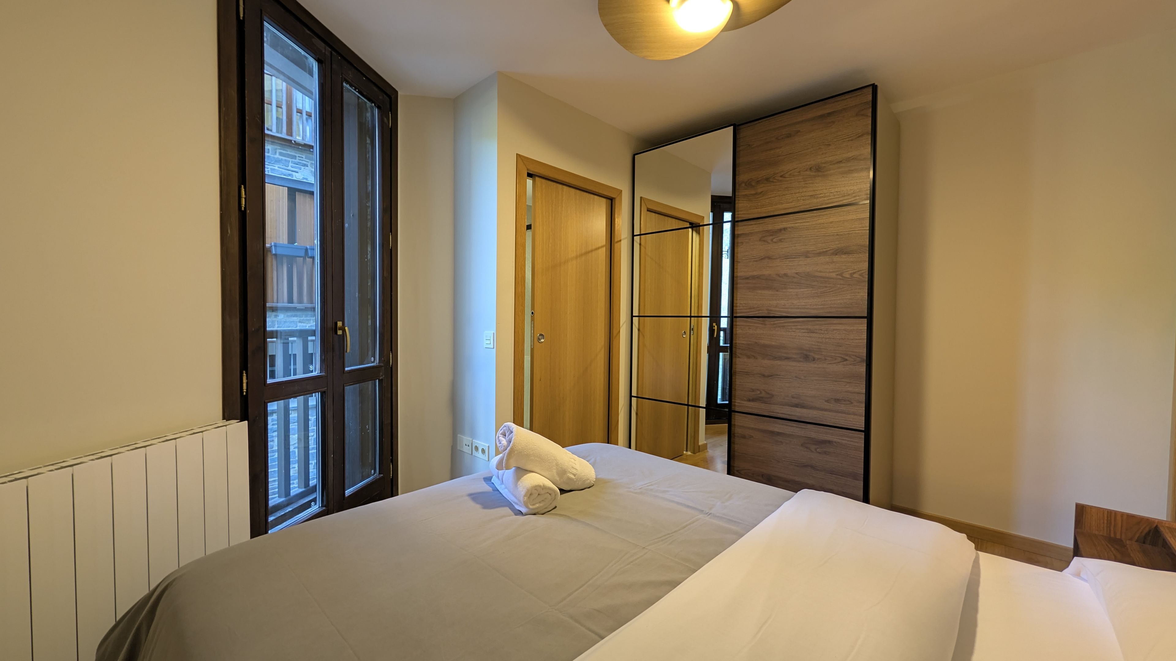 A hotel room with a bed, a large mirror, and a window.