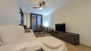 A modern living room with a sofa, a television, and a dining area with chairs and a table. - The Little Prince - tucasaenlospirineos (Escarrilla)