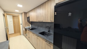 A modern kitchen with wooden cabinets, a black countertop, and a built-in microwave. - The Little Prince - tucasaenlospirineos (Escarrilla)
