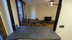 Ein Essbereich mit Tisch, Stühlen, einem Fernseher und einem Deckenventilator.