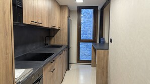 Eine moderne Küche mit Holzschränken, einer schwarzen Arbeitsplatte und einem eingebauten Ofen.