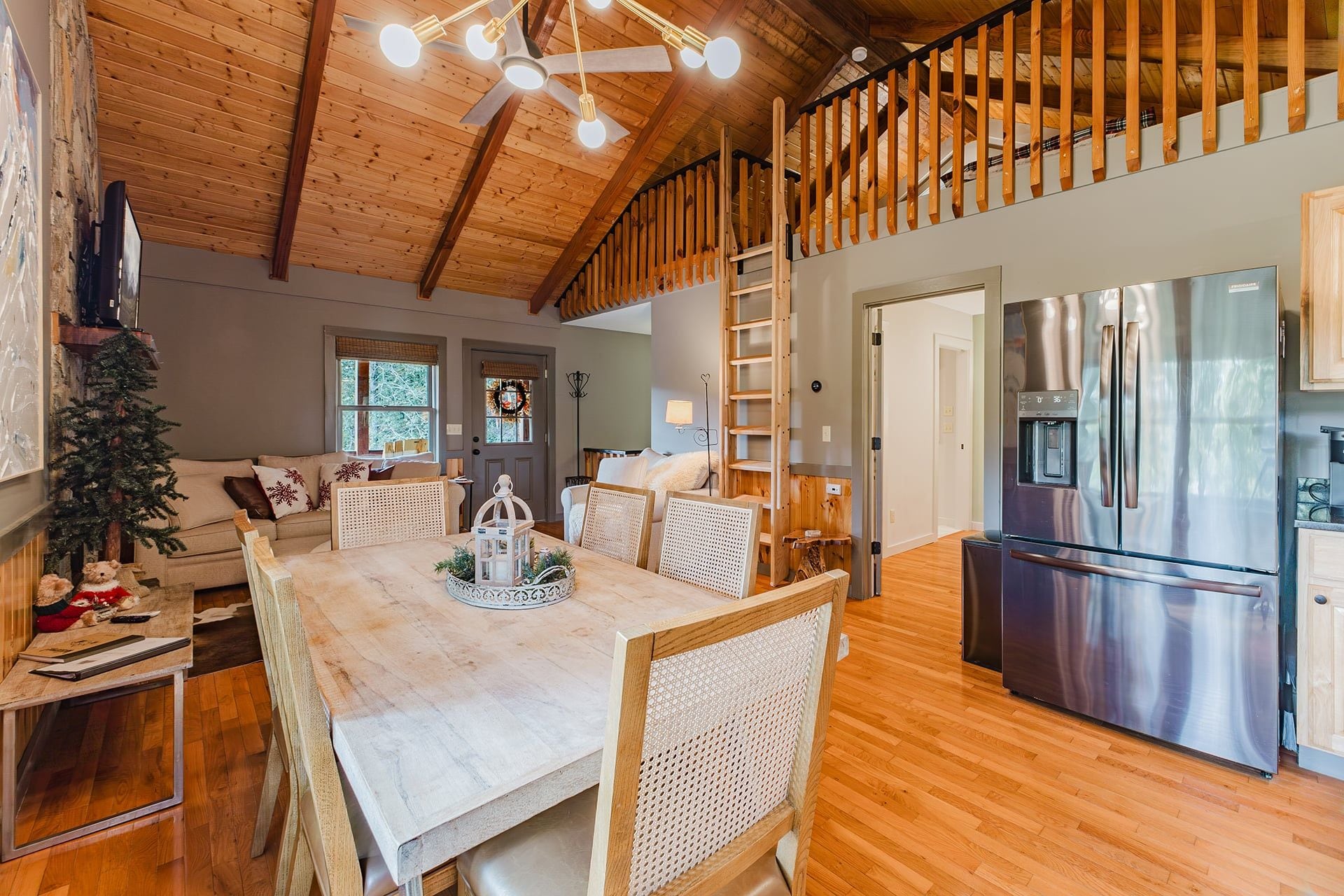 A spacious kitchen with a stainless steel refrigerator, wooden flooring, and a dining area with a table and chairs.