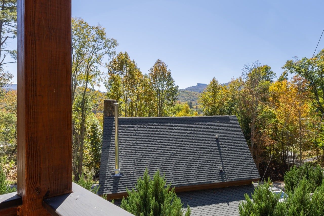 A building with a sloped roof, surrounded by trees and a clear sky.