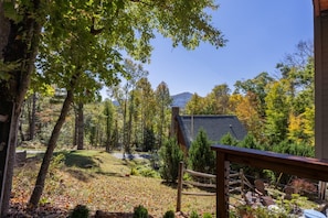 A forested area with a building, a wooden deck, and outdoor seating. - A Cozy Mountain House Near Downtown Banner Elk (Banner Elk)