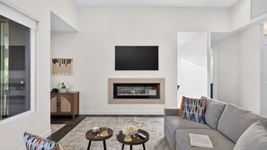 A modern living room with a fireplace, a flat-screen TV, and a grey sofa. - Casa Alta by Avantstay Covered Lounge + Fire Pit + BBQ Red Rock Views (Sedona)