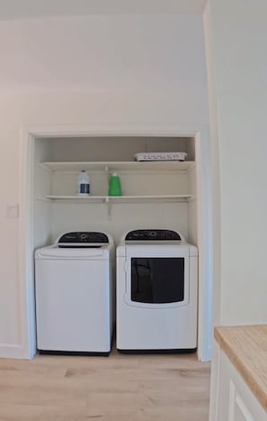 A laundry room with two washing machines and a shelf with cleaning supplies. - Modern Delson Home South Shore Montreal (Delson)