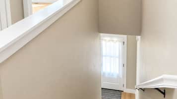 Eine Treppe mit einer Zwischenplattform, eine Tür zu einem anderen Raum und ein Fenster mit Jalousien.