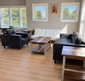 Een moderne woonkamer met een bank, fauteuils, een salontafel en een eettafel.