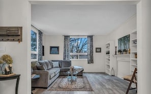 Ein Wohnzimmer mit grauem Ecksofa, einem Couchtisch und einem Kamin.